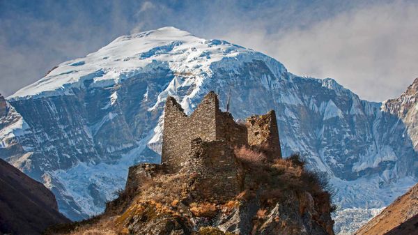 An ancient dzong in Bhutan with Jomolhari, a peak in the Himalayas, in the background