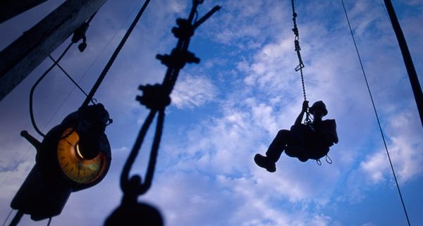 A worker returns to earth after lubricating the top of a drilling rig