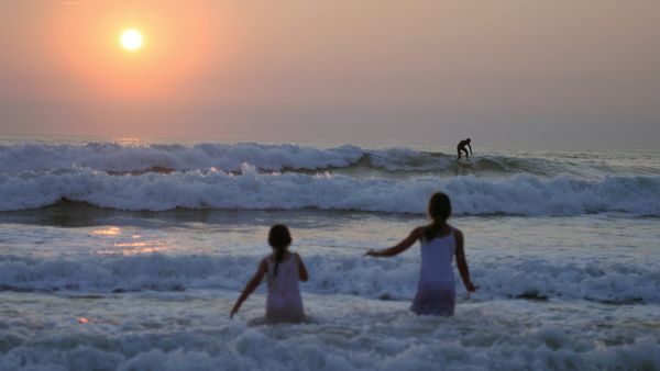 Deux fillettes en pleine baignade devant un coucher de soleil à Lacanau, France