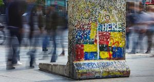 Berliner Mauerdenkmal am Potsdamer Platz. Passanten laufen an einem einzelnen Segment der Berliner Mauer am Potsdamer Platz vorbei, welches an seiner ursprünglichen Position belassen wurde und nun als Denkmal dient. (© Jon Hicks/Corbis) &copy; (Bing Germany)