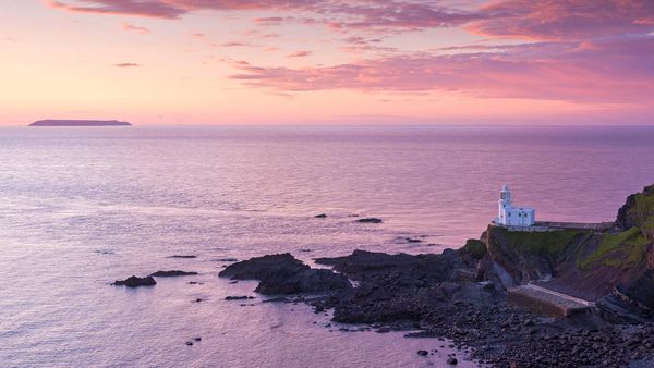 Hartland Point Lighthouse and Lundy Island beneath a colourful sunset, North Devon