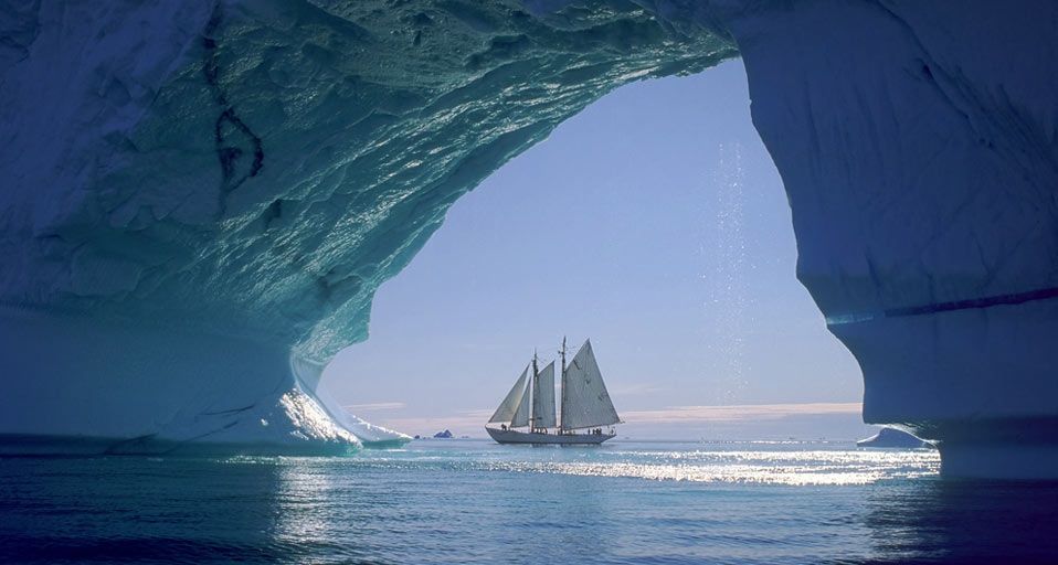Iceberg arch and sailboat off the coast of Greenland