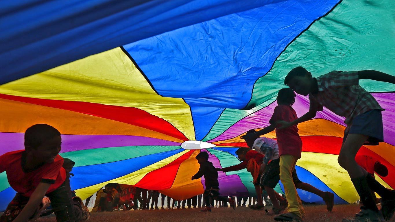 Children play under a parachute in Kolkata, India, for International Day of Friendship