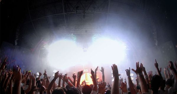 Party goers dance with their arms raised during a dance rave party music festival in Melbourne