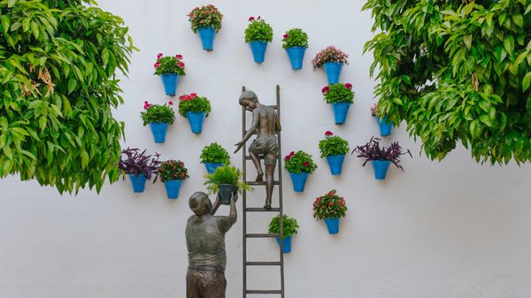 Figura de bronce de un abuelo y su nieto cuidando de las plantas y las flores, Córdoba, España