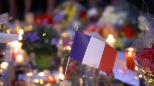 Drapeau français au milieu des fleurs et bougies d’un mémorial en hommage aux victimes de l’attentat de Nice, le 15 juillet 2016 à Nice (© AP Photo/Luca Bruno)(Bing France)