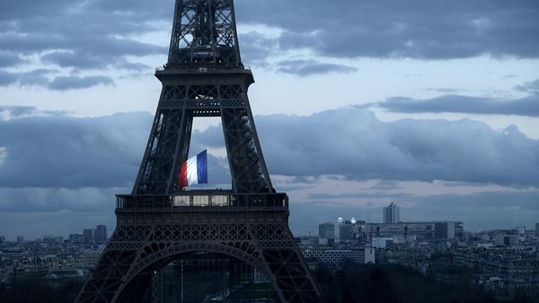 Le drapeau français flottant au centre de la Tour Eiffel, le 11 mars 2020, lors d’une cérémonie pour la première Journée nationale d’hommage aux victimes du terrorisme