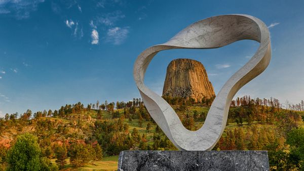 The 'Circle of Sacred Smoke' sculpture by Junkyu Muto frames Devils Tower in Wyoming