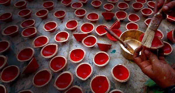 An Indian man paints earthen lamps for the forthcoming Diwali in India