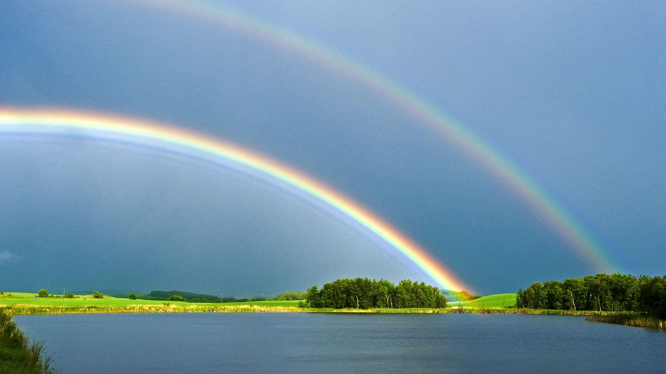 Prairie slough with farmland and rainbow in the background, near Bruxelles, Manitoba
