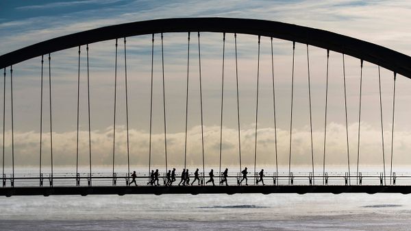 A group of joggers run across the Humber Bay Arch Bridge in Toronto, Canada