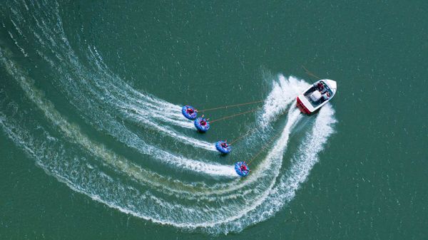 A speedboat tows four “tubers” on Abbey Lake in Surrey, England