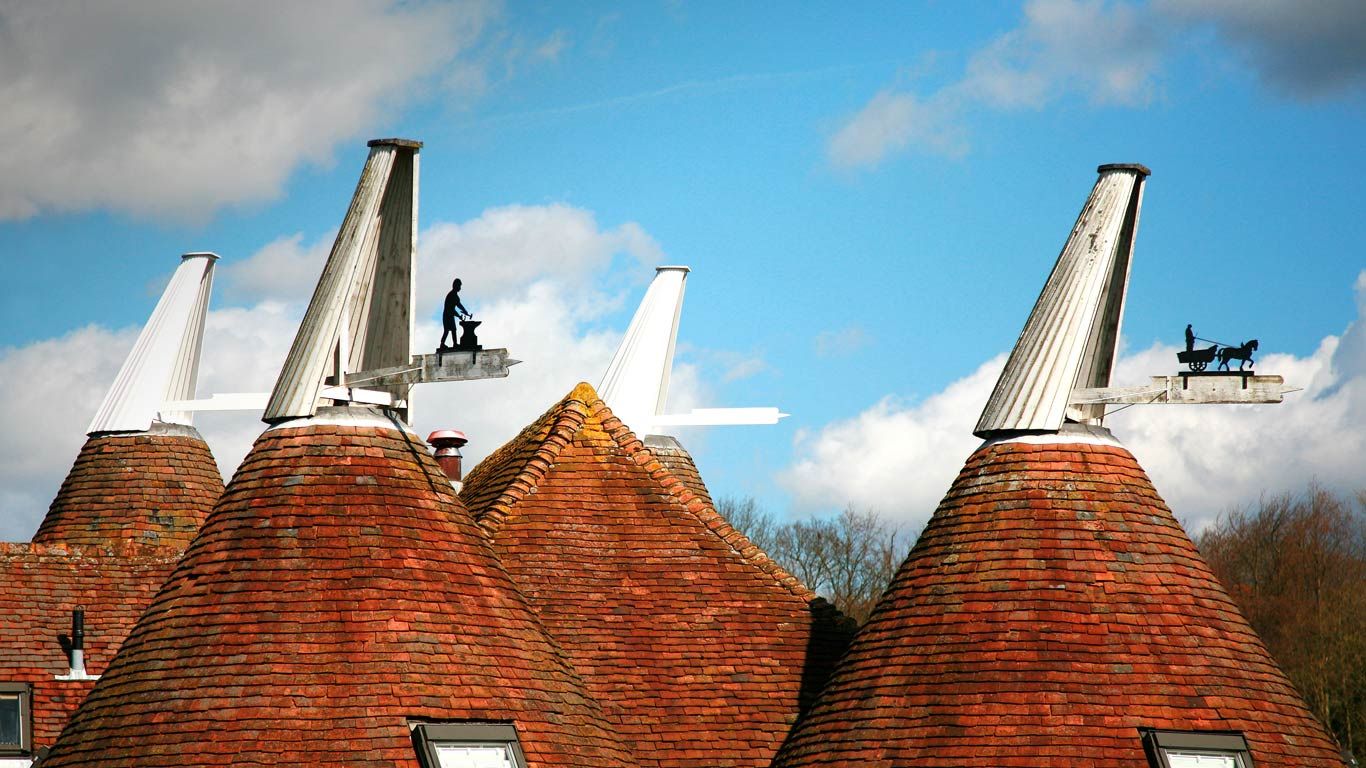 Oast house roofs with wind vanes decorated with agricultural scenes on a farm in Kent