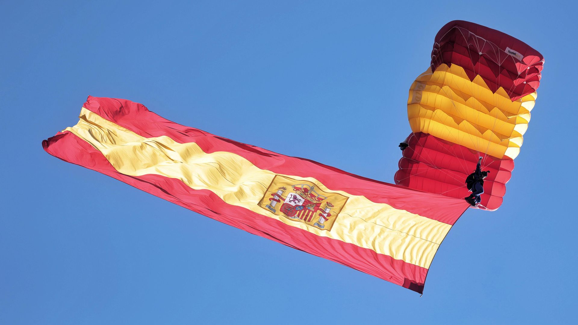 Paracaidista despliega la bandera española en el aire durante el desfile militar en el Día de la Hispanidad, Madrid, España