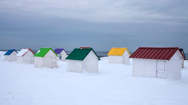 Cabanes aux toits colorés recouvertes de neige à Gouville-sur-Mer, Normandie