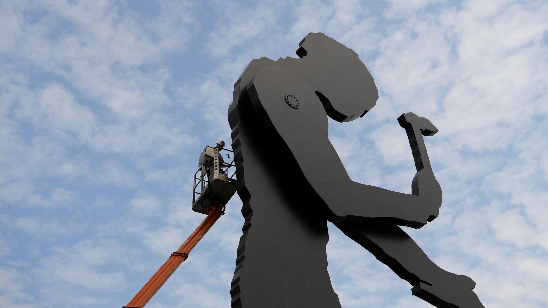A worker painting the Hammering Man, a sculpture by Jonathan Borofsky, in Frankfurt, Germany