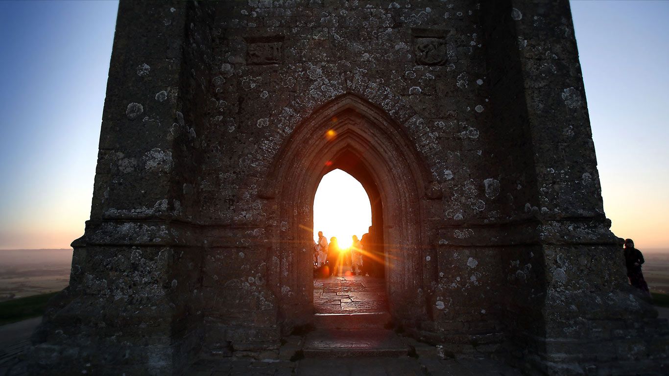 People gather for a Beltane dawn celebration service in front of St Michael's Tower on Glastonbury Tor, England