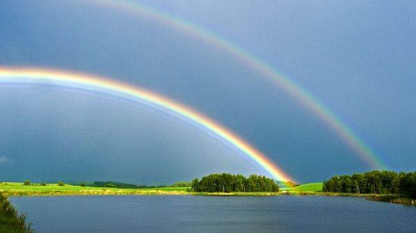 Prairie slough with farmland and rainbow in the background, near Bruxelles, Manitoba