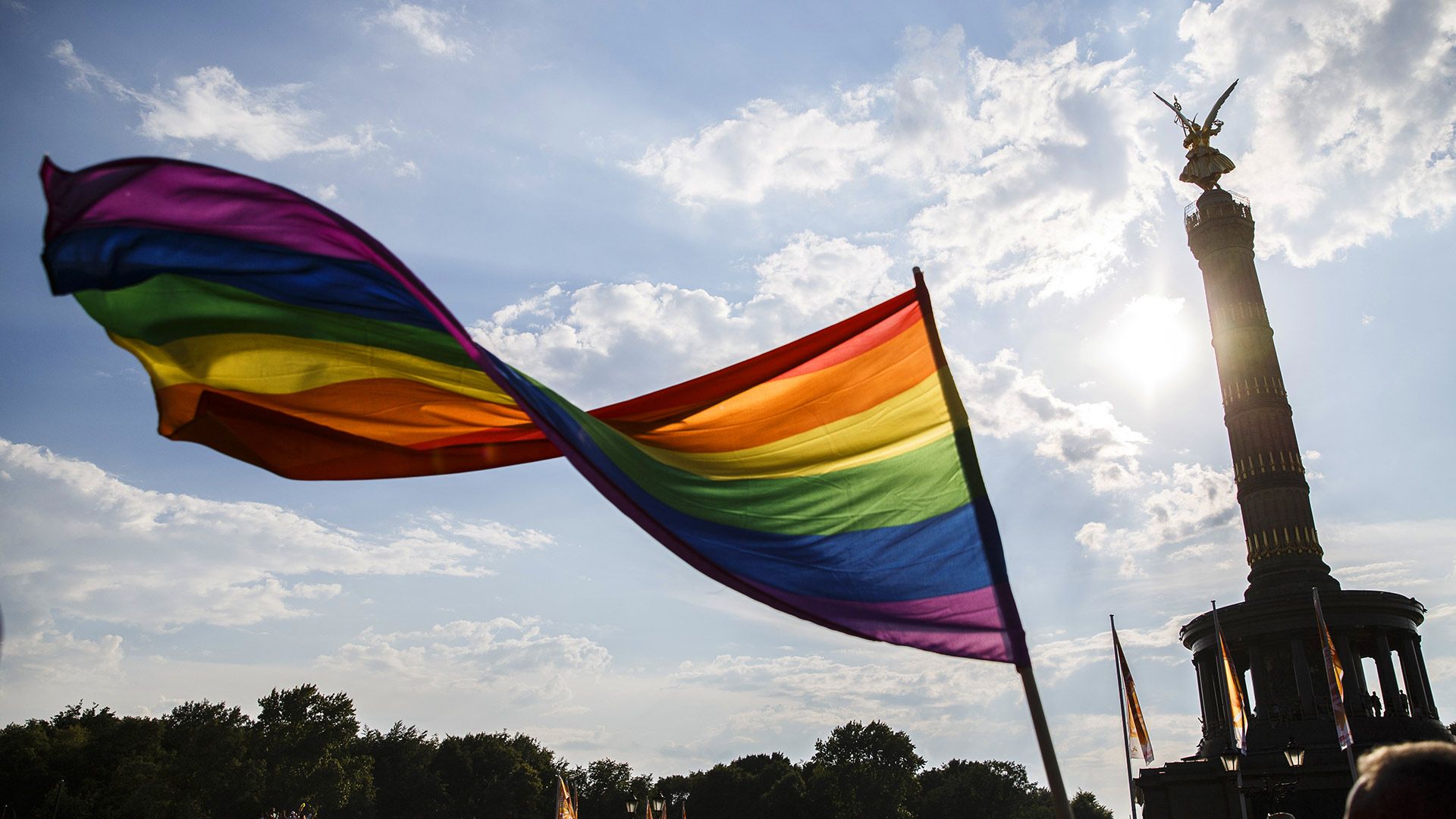 Ein Teilnehmer schwenkt die Regenbogen-Flagge auf dem 40. Christopher Street Day vor der Siegessäule am 28. Juli 2018 in Berlin, Deutschland