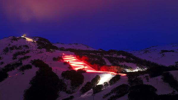 Skier with red torch at dusk in Thredbo, New South Wales