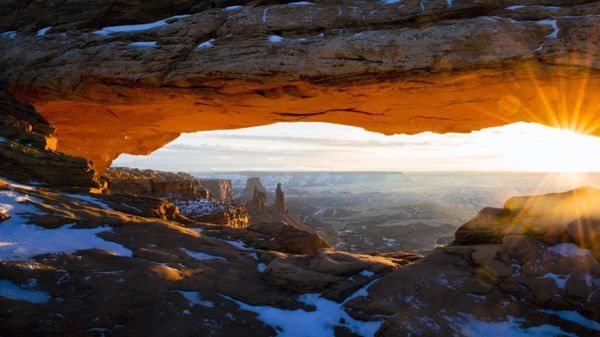 The sun peeks through Mesa Arch in Canyonlands National Park, Utah