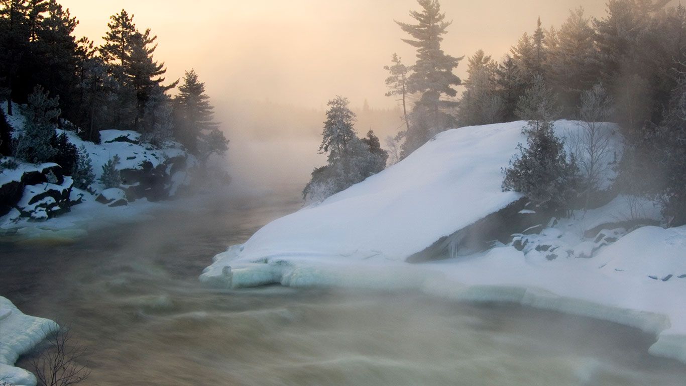 Tree silhouettes and rising mists near rapids of Wanapitei River, Wanup, Ontario