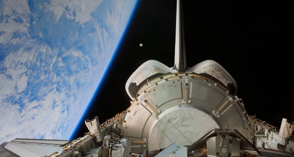 Space Shuttle Discovery backdropped by Earth and the Moon