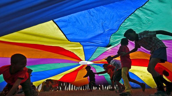 Children play under a parachute in Kolkata, India, for International Day of Friendship