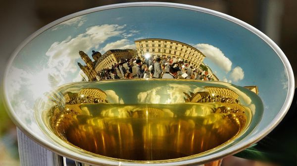 A marching band is reflected in the bell of a horn during Oktoberfest in Munich, Germany