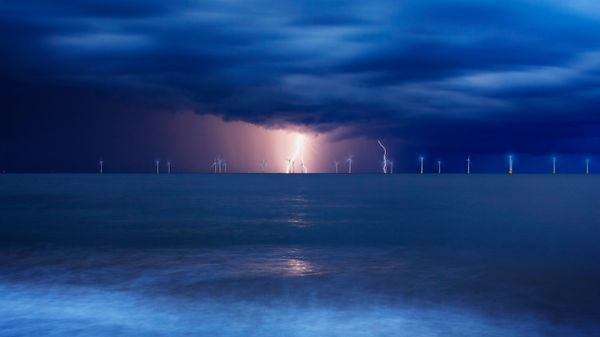 Offshore wind farm at Great Yarmouth in Norfolk in a lightning storm, England