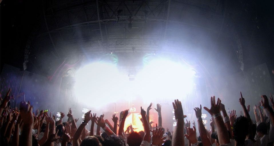 Party goers dance with their arms raised during a dance rave party music festival in Melbourne