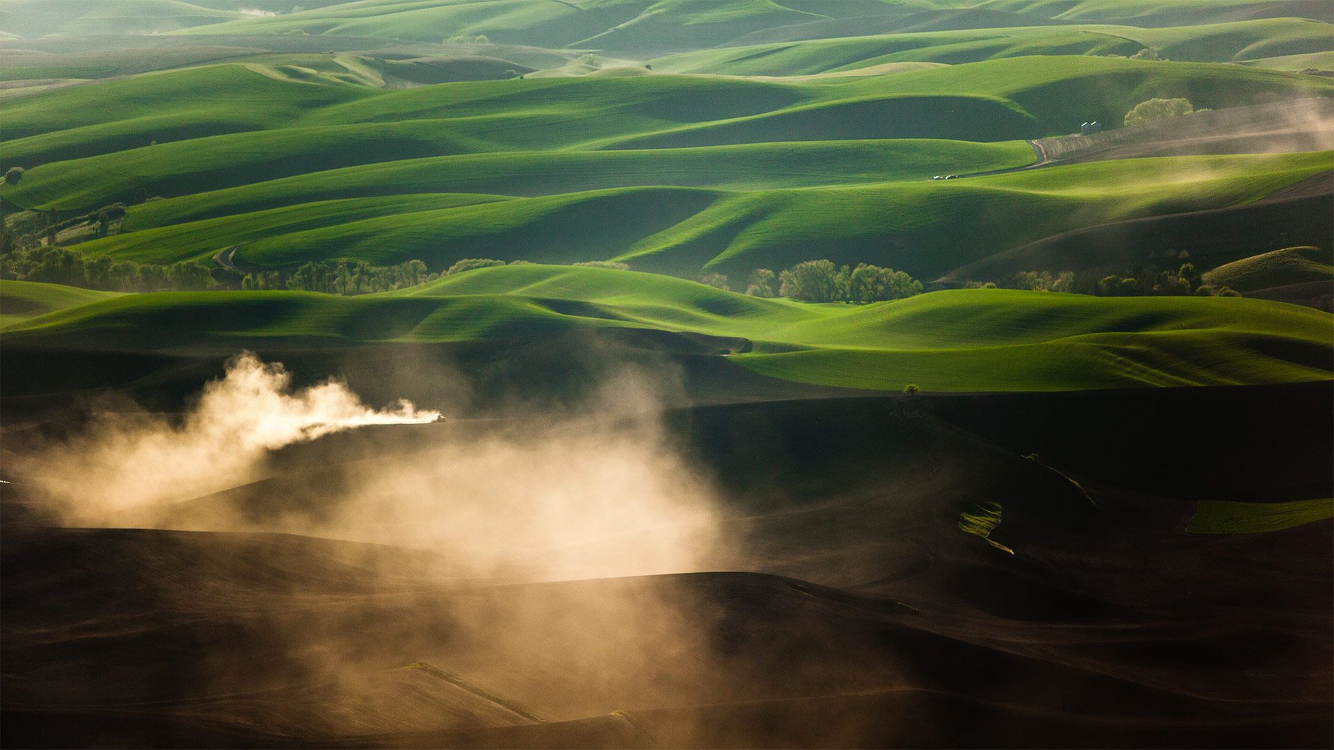 A tractor kicks up dust while tilling fields on the Palouse near Pullman, Washington