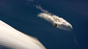 高山滑雪，滑雪板在转弯时溅起粉末 (© Jeff Curtes/Aurora Photos)(Bing China)