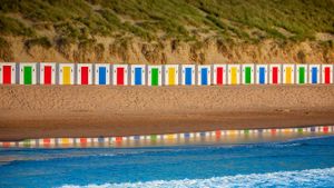 Beach huts reflecting in the water at Woolacombe Beach, Devon, England (© Fingerszz/Getty Images)(Bing New Zealand)
