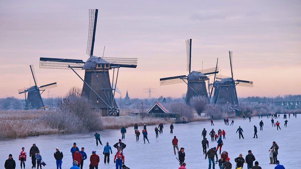 Skating on a frozen canal near the windmills at Kinderdijk, Netherlands