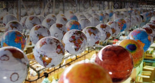 Globes suspended from conveyor track at factory