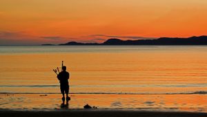 苏格兰，海滩上的风笛手 (© ColsTravel/Alamy)(Bing China)