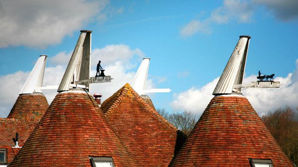 Oast house roofs with wind vanes decorated with agricultural scenes on a farm in Kent