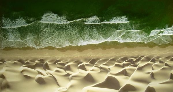Waves of water meet waves of sand on the beach of the Pacific ocean near Paracas, Peru