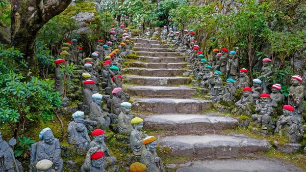 Small rakan statues line the stone pathway to the Daisho-in Temple, Miyajima, Japan